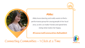 A cheerful young woman holding a dandelion is featured in the left segment of the image within a circular frame accented by yellow and orange colours. To her right, the text reads 'Abby: Abby loves dancing and really wants to find a performance group for young people in her local area, so she can make friends and spend time doing what makes her happy. #ConnectedCommunities #aDoddleIt.' The bottom of the image features the slogan 'Connecting Communities – 1 Click at a Time' alongside the logo for aDoddle.org, symbolising the organisation's aim to connect individuals with community resources.